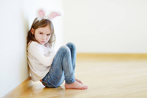 Angry little girl wearing bunny ears stock photo