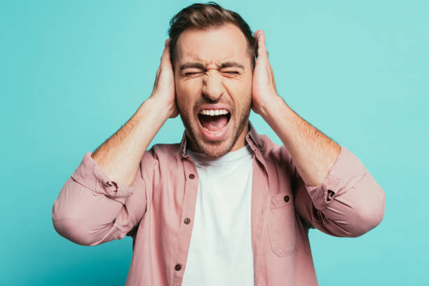 angry man shouting and closing ears, isolated on blue angry man shouting and closing ears, isolated on blue Fingers in Ears stock pictures, royalty-free photos & images