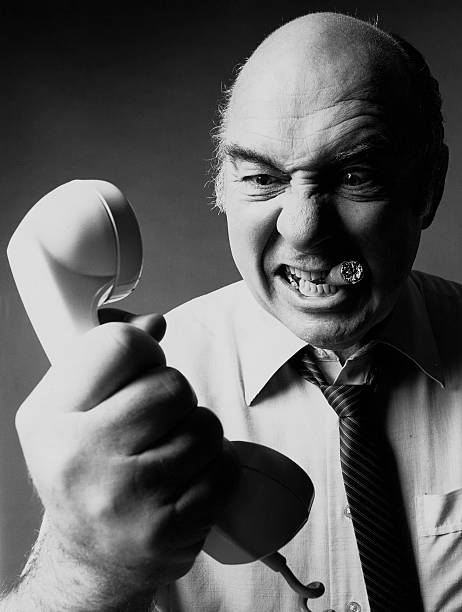 angry man shouting at telephone receiver stock photo