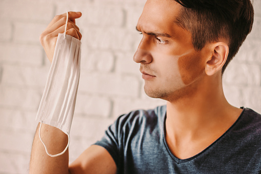 Angry Man With Funny Sunburn Tan Looking At Medical Face Mask Stock Photo - Download Image Now - iStock