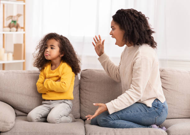 Angry Mother Shouting At Daughter Sitting On Couch At Home Angry Afro Mother Shouting At Offended Daughter Sitting On Couch At Home. Family Problems, Quarrels And Aggression punishment stock pictures, royalty-free photos & images
