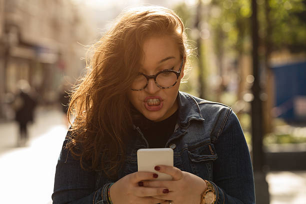 Angry woman using cellphone outdoors. stock photo