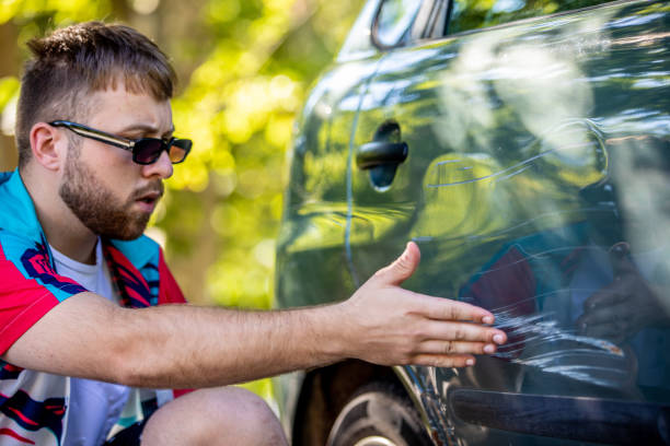 Angry Young Adult Man Pointing at Scratched Car Door Angry Young Adult Man Pointing at Scratched Car Door. dented stock pictures, royalty-free photos & images