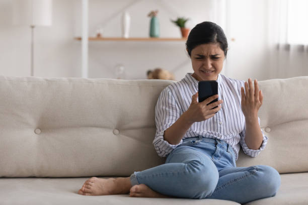 arg ung indisk kvinna läsa spam meddelande på telefonskärmen - bedrägeri telefon bildbanksfoton och bilder