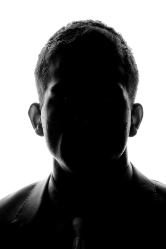 Silhouette of a young man looking looking at the camera.