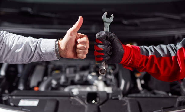 Anonymous man approving job of auto mechanic in workshop stock photo
