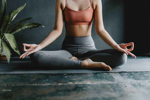 anonyme frau macht yoga zu hause: lotus-position - yoga stock-fotos und bilder