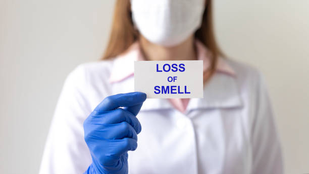 Anosmia loss of sense of smell. Loss of smell text on white paper in hands in protective gloves with blurring doctor on background Anosmia loss of sense of smell. Loss of smell text on white paper in hands in protective gloves with blurring doctor on background scented stock pictures, royalty-free photos & images