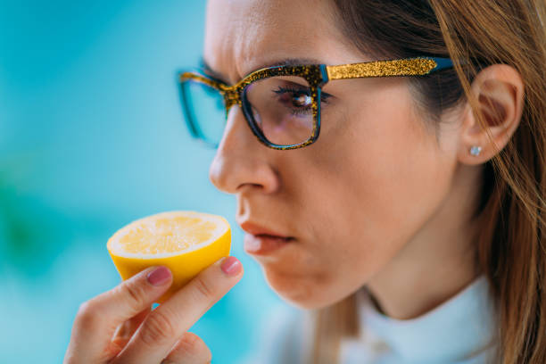Anosmia or smell blindness Anosmia or smell blindness, loss of the ability to smell, one of the possible symptoms of covid-19, infectious disease caused by corona virus. Woman Trying to Sense Smell of a Lemon smelling photos stock pictures, royalty-free photos & images