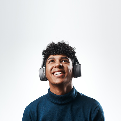 Studio shot of a young man using headphones against a grey background