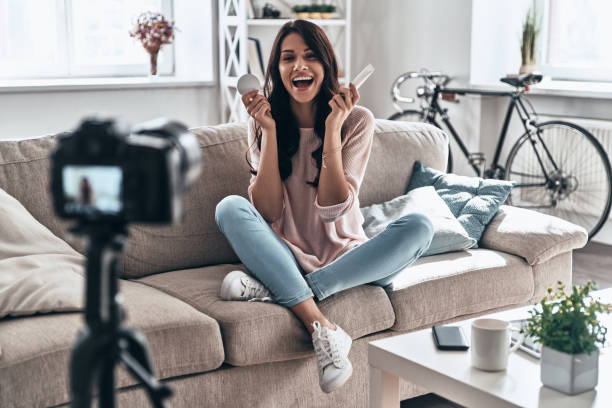 Another video in her vlog. Beautiful young woman holding beauty products and smiling while making social media video influencer stock pictures, royalty-free photos & images