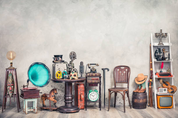 Antique gramophone, chair, old typewriter, retro radio, tape recorder, projector, books, clock, camera, fiddle, mask, cylinder hat, cowboy boots, bow, cane, suitcase. Vintage style filtered photo stock photo