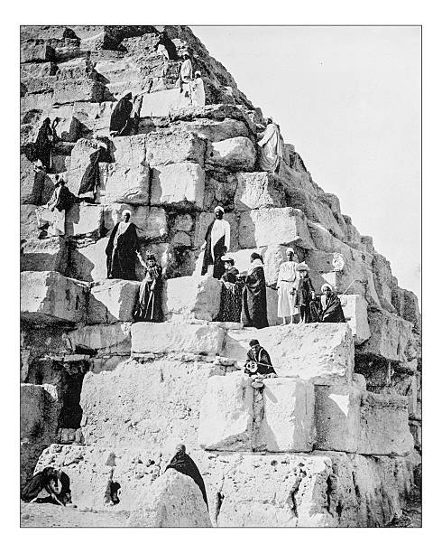 Antique photograph of tourists ascending the Gyza Pyramid (Egypt-19th century) Antique photograph of 19th century tourists ascending the Great Pyramid of Gyza together with some Bedouins.The Great Pyramid of Giza (or Pyramid of Khufu or Pyramid of Cheops) is the largest of the Giza pyramid complex (El Giza, Egypt) archaeology photos stock illustrations
