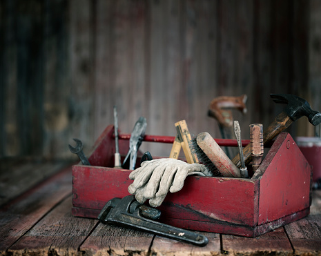 Antique work tools in a red toolbox on an old wood background
