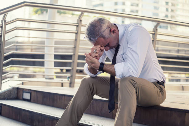 Anxious old businessman in city Anxious senior businessman sitting in steps. Stressed gray hair businessman headache and look down with depress feeling. Business problems, Fired, Unemployed, bankrupt due to covid-19. downsizing unemployment stock pictures, royalty-free photos & images