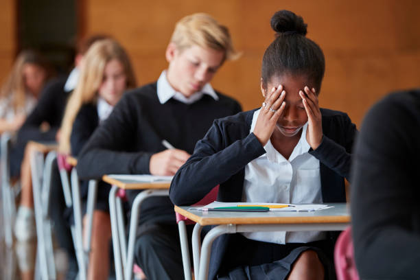 Anxious Teenage Student Sitting Examination In School Hall Anxious Teenage Student Sitting Examination In School Hall exam stress stock pictures, royalty-free photos & images