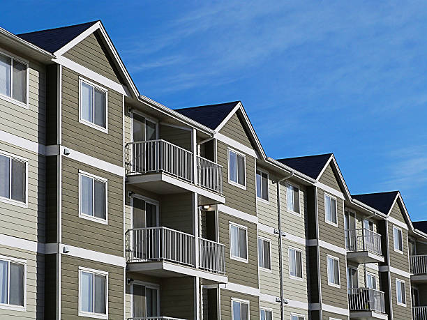 Apartment Complex With Blue Sky A row of a modern apartment complex development with a bright blue sky. flat physical description stock pictures, royalty-free photos & images