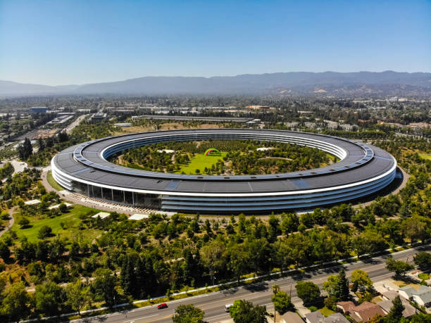 Apple Park Sunnyvale, California, USA - July 30, 2019: Cars driving past Apple Park, an iconic building located in Sunnyvale California. This image was taken on the morning of July 30, 2019. Apple Park serves as the international headquarters of Apple, Inc. The roof contains solar arrays that power the building. headquarters stock pictures, royalty-free photos & images