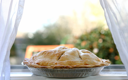 Photo of an hot apple pie cooling on a window ledge.