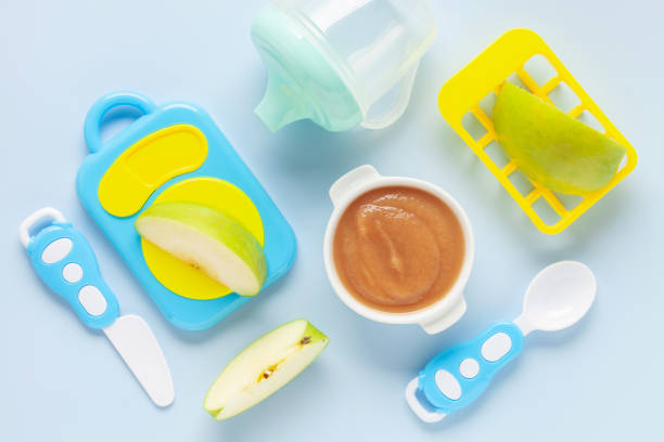 Apple puree in a bowl and toy plastic tableware. Baby food concept. Top View stock photo