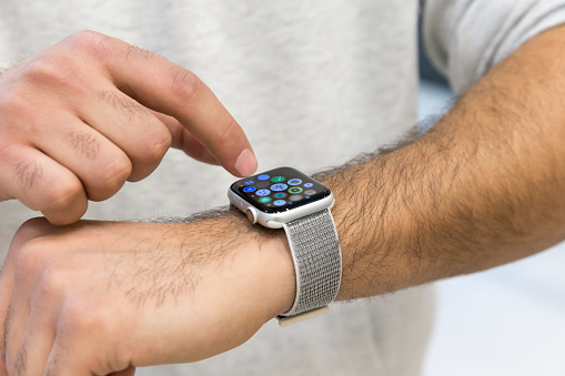 Apple watch shown on hand. Man's finger typing applications on the screen