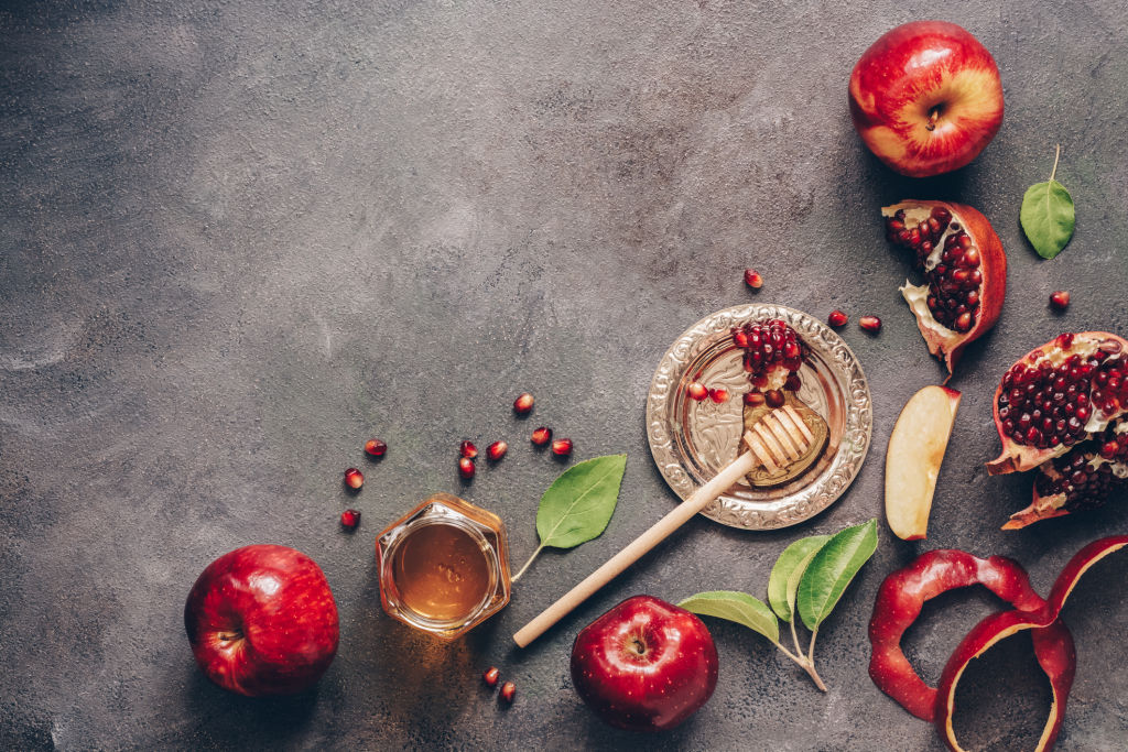 Apples, pomegranate and honey on a dark rustic background. Traditional Jewish food. New Year - Rosh Hashanah. Top view, copy space, flat lay