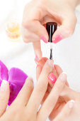 Subject: Manicurist skillfully applying French manicure nail polish on customer's fingernails in beauty spa.