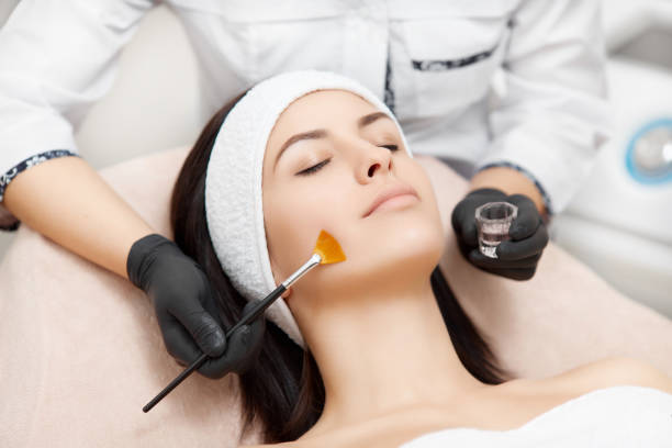Applying of peeling anti-acne mask on face Beautiful woman with smooth skin relaxing and enjoying spa procedures. Beautician applying anti-acne mask, making face peeling. Concept of facial, rejuvenation and regeneration of skin. peeling off stock pictures, royalty-free photos & images
