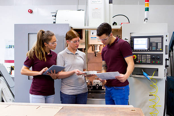 Apprentices in the CNC Workplace, Group of young adults working with a female tutor. 