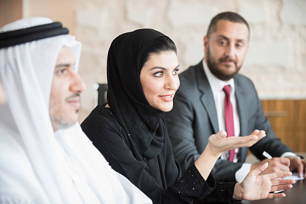 Arab businesswoman in business meeting with colleagues A photo of mature Arab businesswoman talking in a business meeting. Emirati woman is sitting with middle eastern coworkers in board room. Professional woman in traditional abaya and hijab, Dubai, United Arab Emirates, Middle East. agal stock pictures, royalty-free photos & images