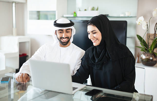 Arab Couple Discussing Business at Home Using Laptop stock photo