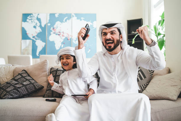 papà e figlio arabi che giocano con i videogiochi a casa - joystick soccer foto e immagini stock