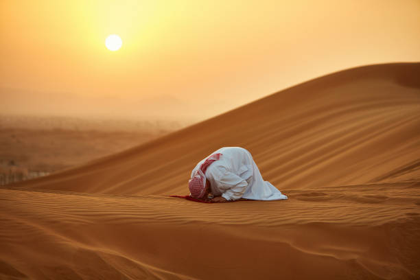 arabe homme priant sur tapis dans le désert pendant le coucher du soleil - prière islam photos et images de collection