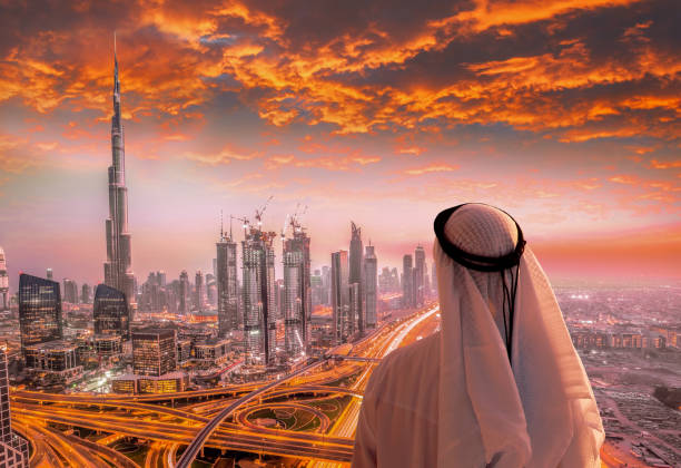 Arabian man watching cityscape of Dubai with modern futuristic architecture in United Arab Emirates. stock photo