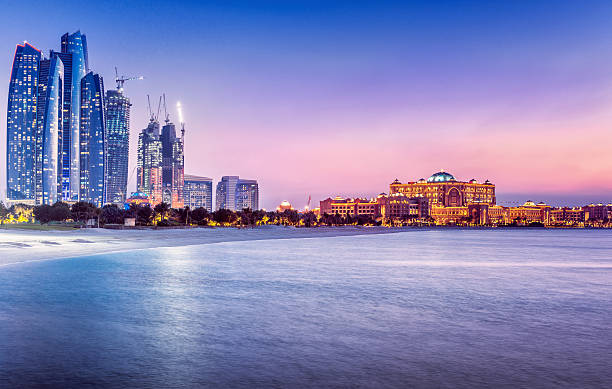 Arabic Nights in Abu Dhabi (UAE) View over the Persian Gulf on Abu´s Dhabi´s skyline, with the landmarks Etihad Towers, newly built skyscrapers and the Emirates Palace at dusk. abu dhabi stock pictures, royalty-free photos & images