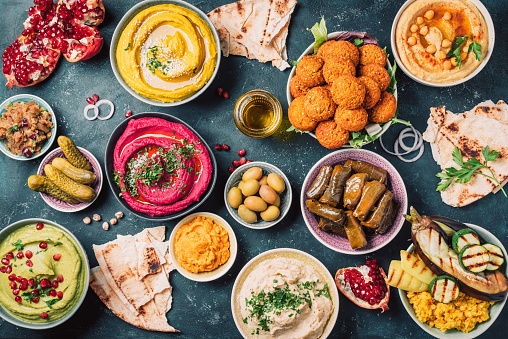 Arabic traditional cuisine. Middle Eastern meze with pita, olives, colorful hummus, falafel, stuffed dolma, babaganush, pickles, vegetables, pomegranate, eggplants. Mediterranean appetizer party idea