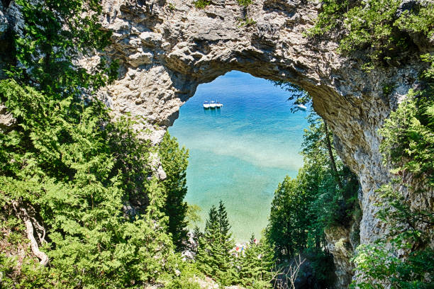 Arch Rock On Mackinac Island Three boats on Lake Huron are moored together underneath Arch Rock on Mackinac Island, Michigan. mackinac island stock pictures, royalty-free photos & images