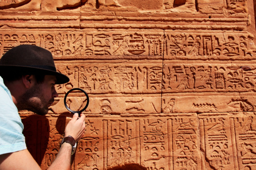 Archeologist reading hieroglyphics with magnifying glass