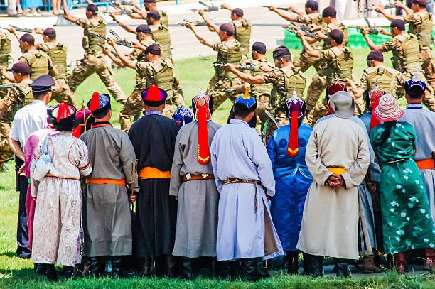 Archers dressed in traditional robes watch army display at Nadaam...