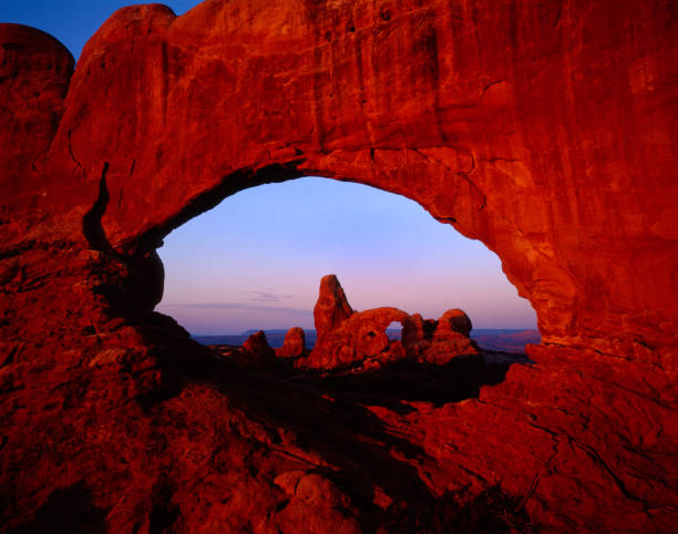 Arches at dawn Utah Turret Arch seen through the North Window at Arches natn'l Park Utah. entrada sandstone stock pictures, royalty-free photos & images