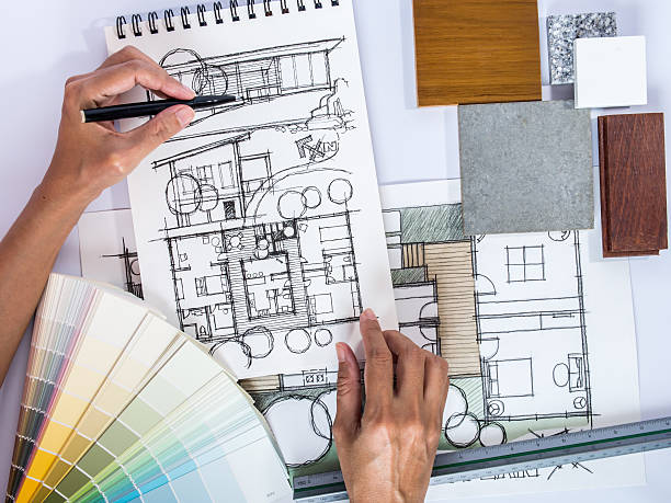 Architect's hands drawing home illustration with material sample stock photo