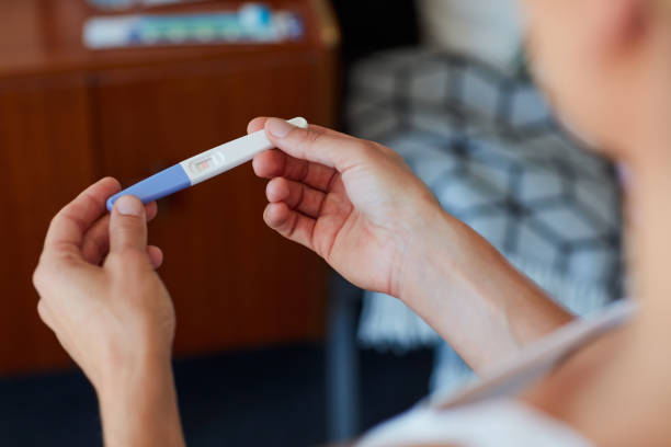 Are these the results she wanted? High angle shot of an unrecognizable young woman holding a pregnancy test in her bedroom at home positive pregnancy test stock pictures, royalty-free photos & images