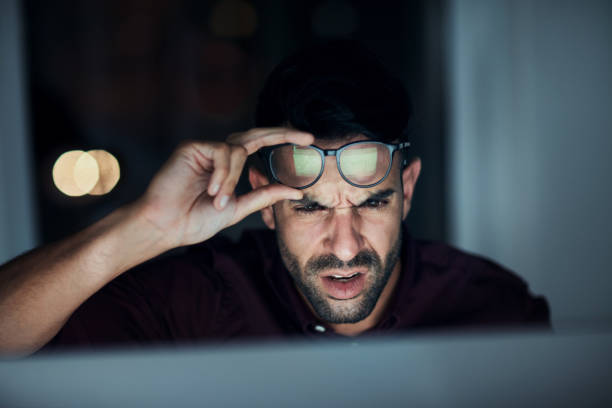 Are you kidding me?? Shot of a young businessman looking angry while using a computer during a late night at work mistake photos stock pictures, royalty-free photos & images
