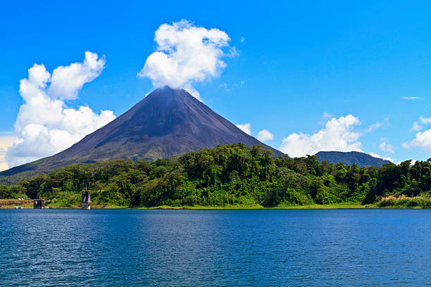 Arenal Volcano and Lake Arenal Volcano 'puffs' out a cloud above the rainforest on the shores of Lake Arenal in Costa Rica volcano stock pictures, royalty-free photos & images
