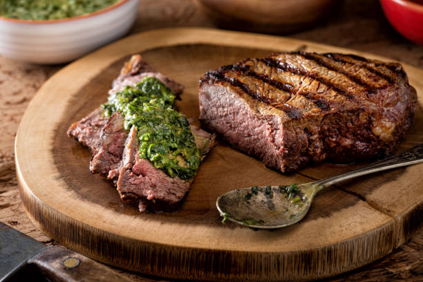 Argentine Style Steak with Chimichurri Sauce A delicious medium rare fire grilled argentina style steak with chimichurri verde sauce. barbecue meal stock pictures, royalty-free photos & images