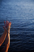 istock Arms of a woman performing a mudra with the background of the sea at sunset 1403062010
