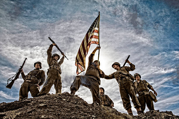 US Army Soldiers on hill with American Flag War World ll solders standing on a hill holding and carrying the American flag. Iwo Jima Concept photo. military invasion stock pictures, royalty-free photos & images
