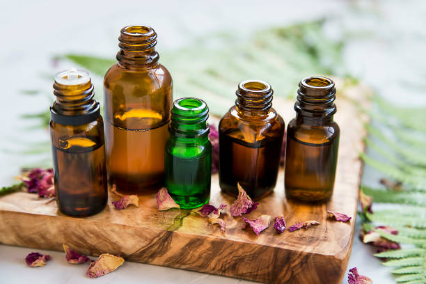 aromatherapie olie flessen met bloemen en groene bladeren, botanische natuurlijke alternatieve schoonheid, kruiden wellness en spa setting - essential oils smell stockfoto's en -beelden