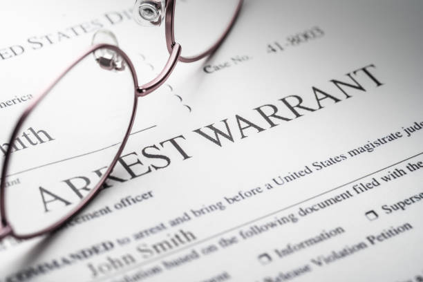 Arrest Warrant document with reading glasses stock photo