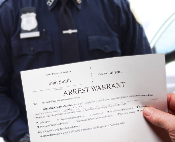 Arrest Warrant with man holding warrant next to police officer stock photo